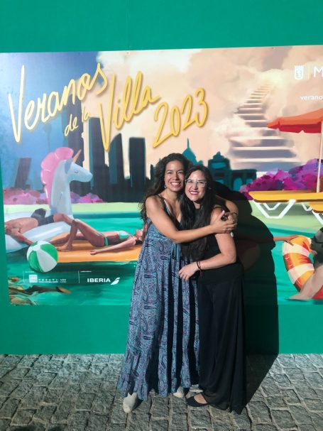 Dos mujeres sonrientes posan juntas frente a un mural titulado "Verano en Villa 2023".