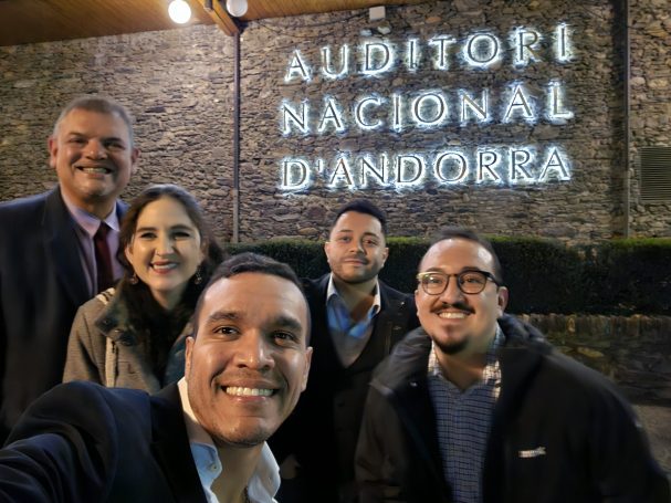 Grupo de cinco personas sonriendo frente al Cartel del Auditorio Nacional de Andorra.